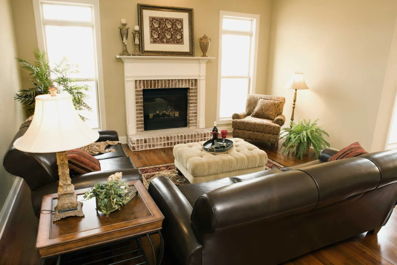 Close-up of a brown couch styled with cream pillows and a warm floor lamp.
