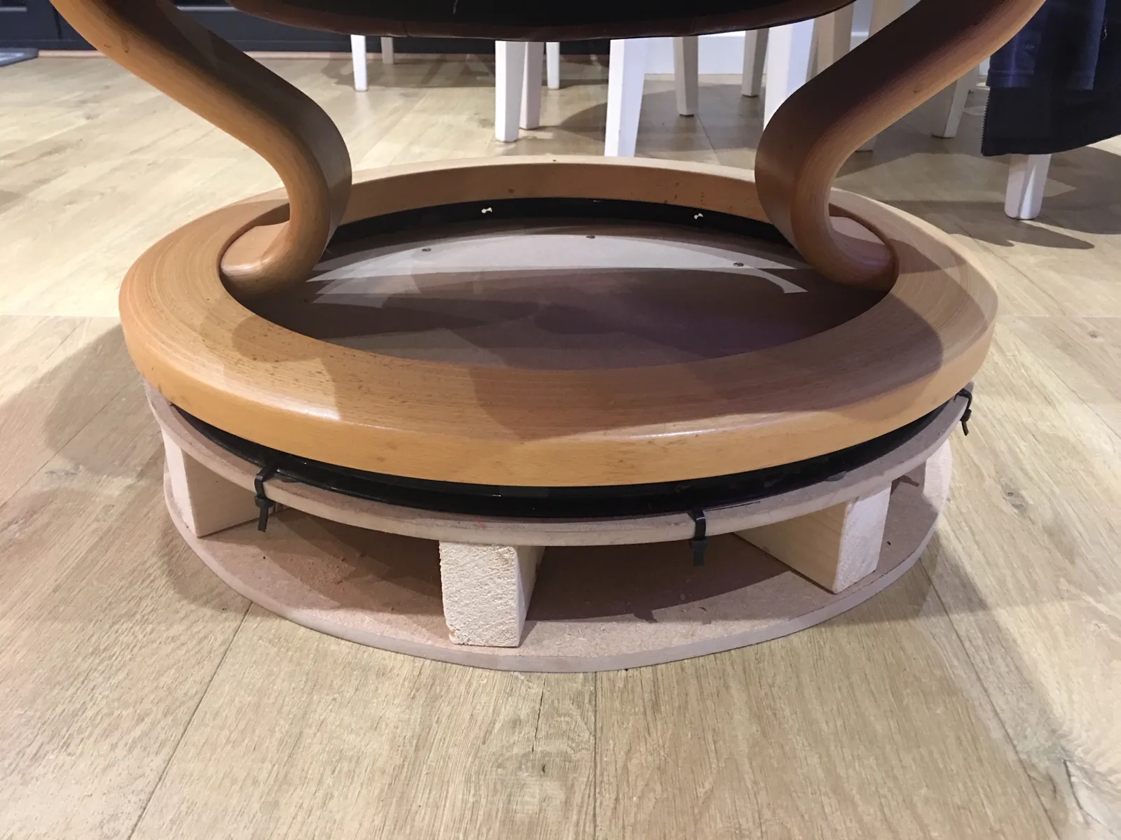A hand reaching for the height adjustment lever under an office chair.