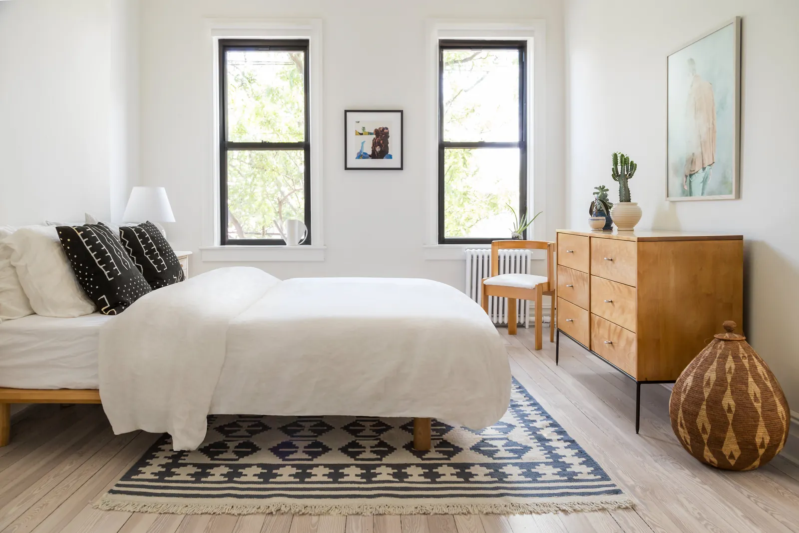 A light-colored linen chair positioned away from the window to keep the bedroom bright.