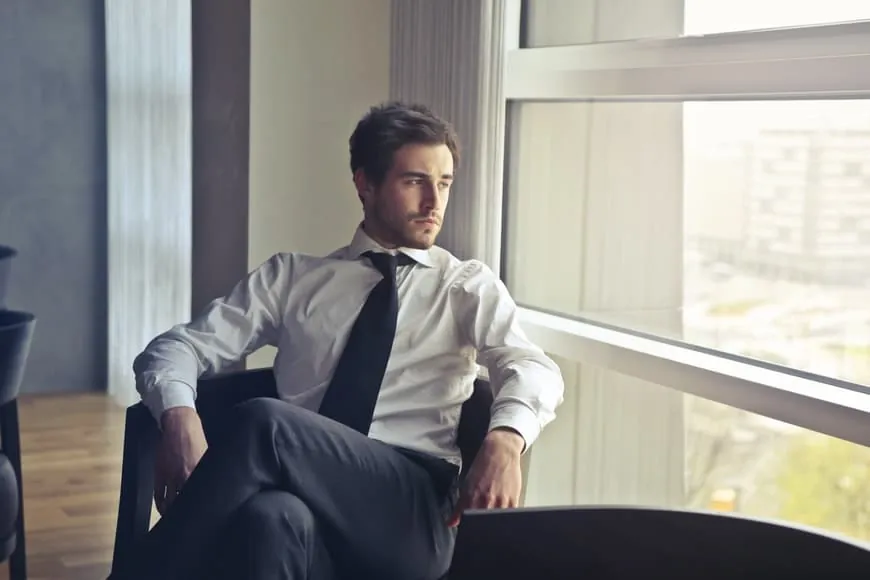 A person demonstrating a tall and elongated sitting posture on a wooden chair.