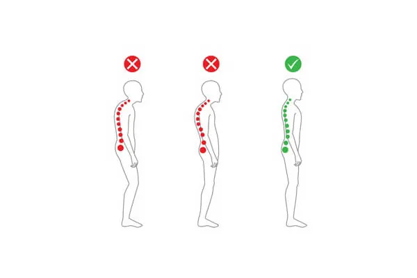 A person stands against a wall to practice correct spine alignment.